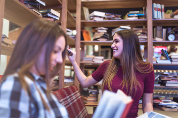 Two young female college students reading books in library