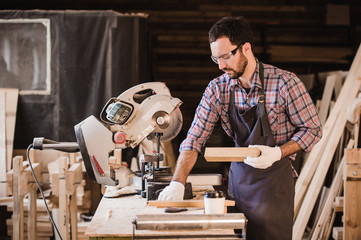 profession, carpentry, woodwork people concept - carpenter with wood plank and notebook checking...