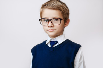Portrait of a serious little boy in spectacles and vest.