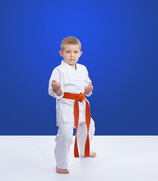On a blue background an athlete is standing in the rack karate