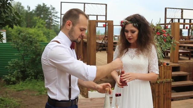 The groom opens the bottle with sand. Wedding tradition sand mix.