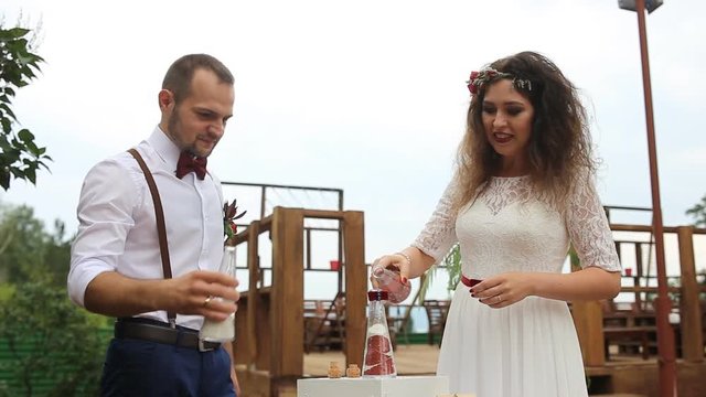 The couple take turns to pour the sand into the bottle. The sand mix.