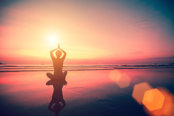 Silhouette of a woman yoga on sea sunset.