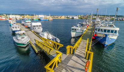 Bona Vista, Newfoundland fishing village.  Wide angle view of L shaped dock. Boats tied up - in for the day, bright sunshine on calm coastal water. © valleyboi63