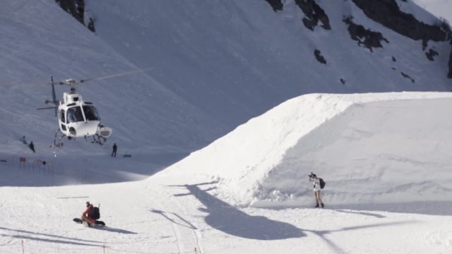 Helicopter take off on ski resort. Snowy mountains. Cameraman. Sunny day. Slow motion