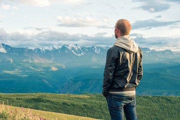 Traveler stay on top of a mountain and looks into the distance. Mountains.