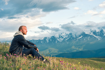Traveler sitting on top of a mountain and looks into the distance. Mountains.