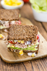 Wooden table with Tuna sandwich (on wholemeal bread; selective f