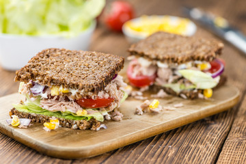 Wooden table with Tuna sandwich (on wholemeal bread; selective f