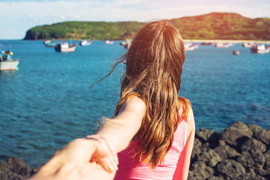 Woman discovering tropical sea holding boyfriend's hand.