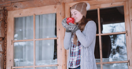 Woman with Cup of Hot Tea or Coffee Walks out the Cozy House on