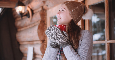 Woman with Cup of Hot Tea or Coffee Walks out the Cozy House on