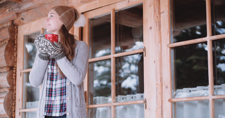 Woman with Cup of Hot Tea or Coffee Walks out the Cozy House on