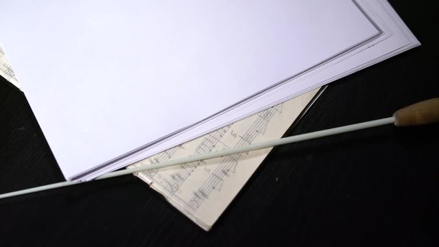 View of music notes and conductor's stick on table