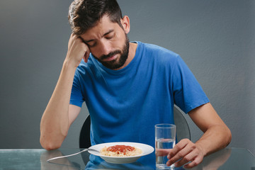 Portrait of man with no appetite in front of the meal. Concept of loss of appetite