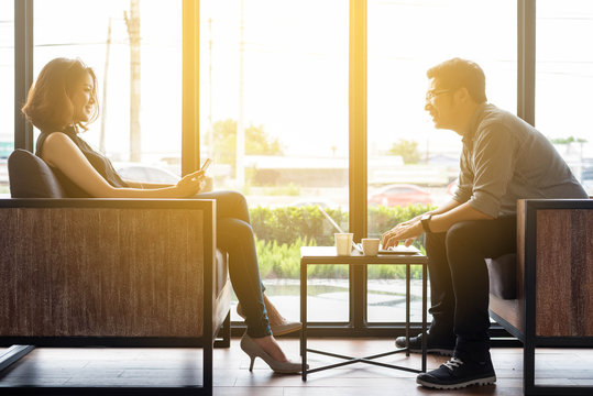 Couple using smartphone and laptop in coffee shop together with