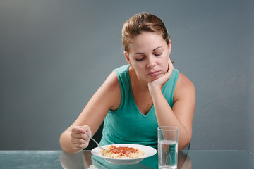 Portrait of woman with no appetite in front of the meal. Concept of loss of appetite