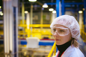 portrait of a woman in a white robe, standing on the background of the production line at the...