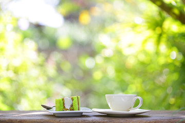 White coffee cup with green cake at outdoor