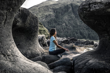 Young woman is sitting among the curve stones in Norway