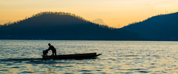 Obraz premium silhouette of a man are boating in the dam on the morning.