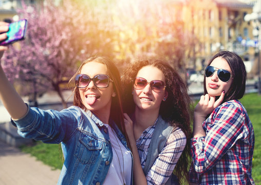 Young happy teenage girls making selfie and having fun in summer park
