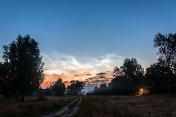 Fototapeta na wymiar noctilucent clouds in the village at dawn