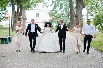 Fine wedding couple with bridesmaids at beige dress and groomsma