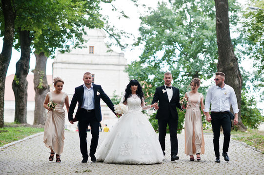 Fine wedding couple with bridesmaids at beige dress and groomsma