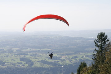 Gleitschirmflieger über dem Hotzenwald mit rotem Gleitschirm
