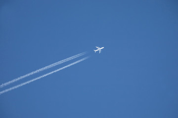 white jet airplane flying high in the blue sky