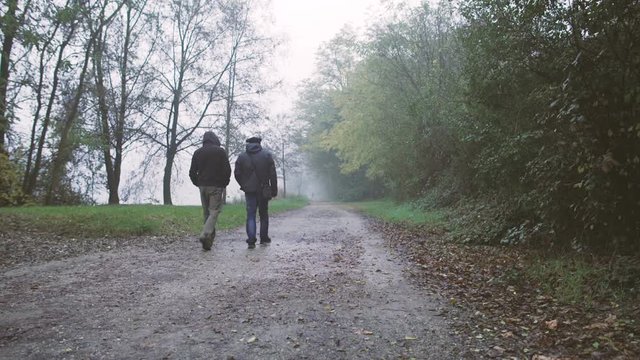 Two men walking in a country trail in the mist