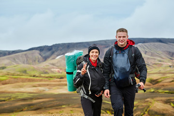 couple joyfull hikers on the trail in the Islandic mountains. Trek in National Park Landmannalaugar, Iceland