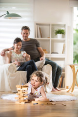 Cheerful family at home. little girl plays with a wooden game