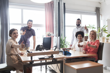 happy creative team showing thumbs up in office