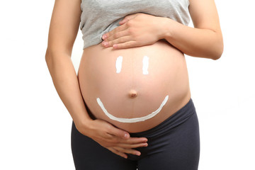 Cream happy smiley face on the belly of pregnant woman isolated on white