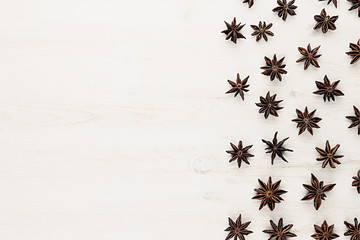 Anise stars spice pattern  on white wood background. Christmas decorative frame. Top view.