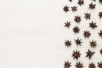 Fototapeta na wymiar Anise stars spice pattern on white wood background. Christmas decorative frame. Top view.