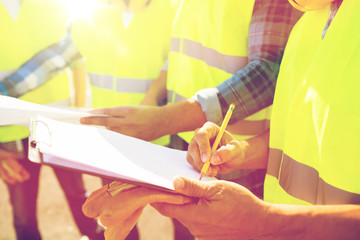 close up of builders in vests writing to clipboard