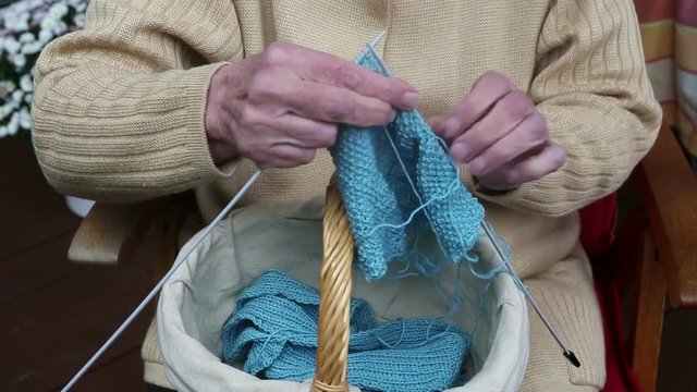 closeup of older woman knitting a scarf
