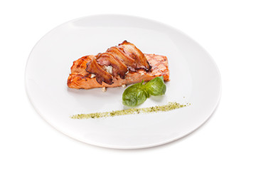 A piece of salmon steak with bacon and cheese.
