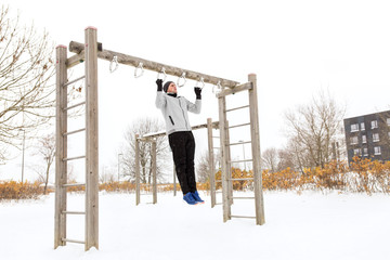 young man exercising on horizontal bar in winter