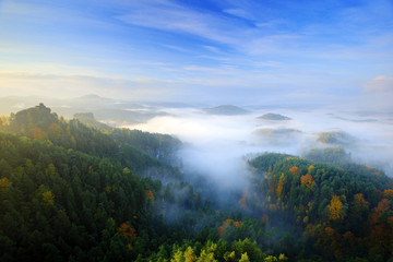 Czech typical morning autumn landscape. Hills and villages with foggy sky. Morning fall valley of Bohemian Switzerland park. Hills with fog, landscape of Czech Republic, Ceske Svycarsko, wild Europe.