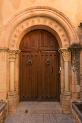 Puerta antigua de madera con arco y columnas de piedra.