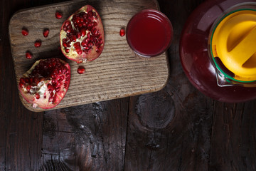 pomegranate juice with sliced pomegranate on a wooden board.