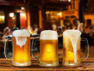 cold glass mug of beer with foam on the background of the street