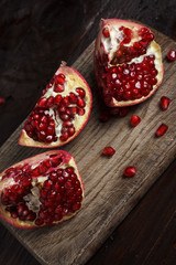 cut part of pomegranate on a wooden board on a wooden background.
