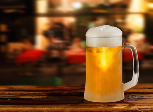 cold glass mug of beer with foam on the background of the street