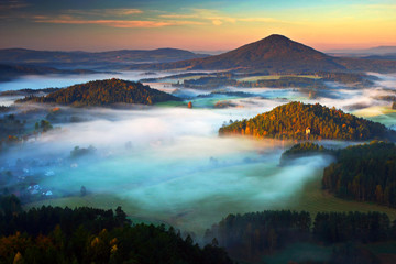 Czech typical autumn landscape. Hills and villages with foggy morning. Morning fall valley of Bohemian Switzerland park. Hills with fog, landscape of Czech Republic, Jetrichovice, Ceske Svycarsko.