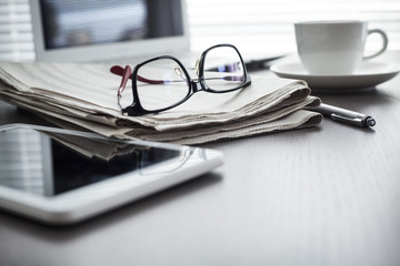 Newspaper with tablet on table